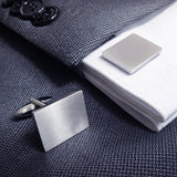 Rechthoekige gematteerde machetknopen gedragen op colbert en overhemd met manchetten