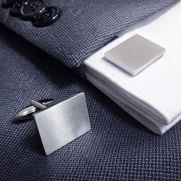 Rechthoekige gematteerde machetknopen gedragen op colbert en overhemd met manchetten